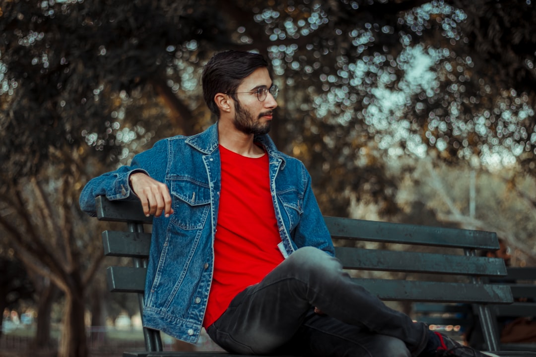 woman in blue denim jacket sitting on brown wooden bench