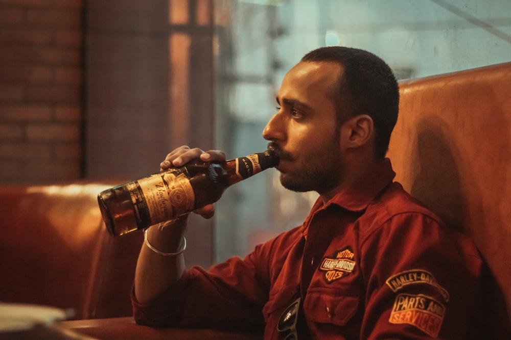 a man sitting in a booth drinking from a bottle