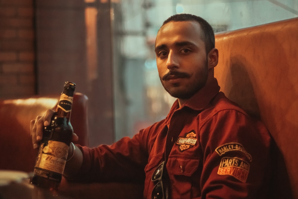 man in red and black zip up jacket holding beer bottle