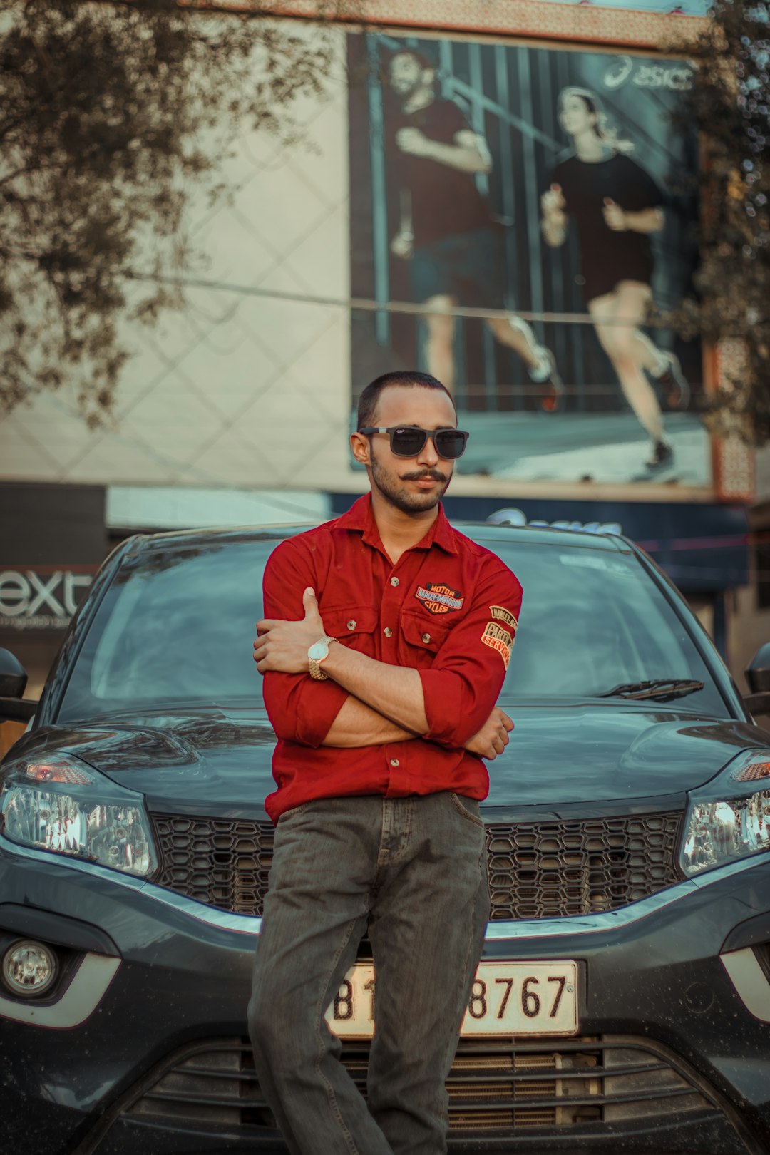 man in red dress shirt and brown pants standing beside black mercedes benz car