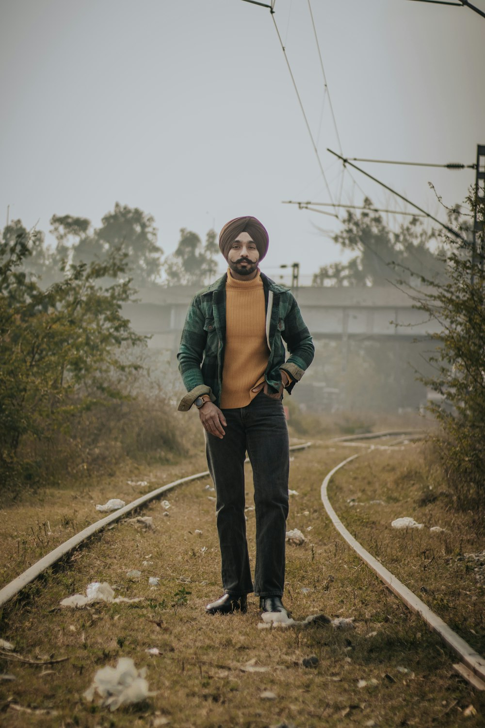 man in green jacket standing on dirt road during daytime