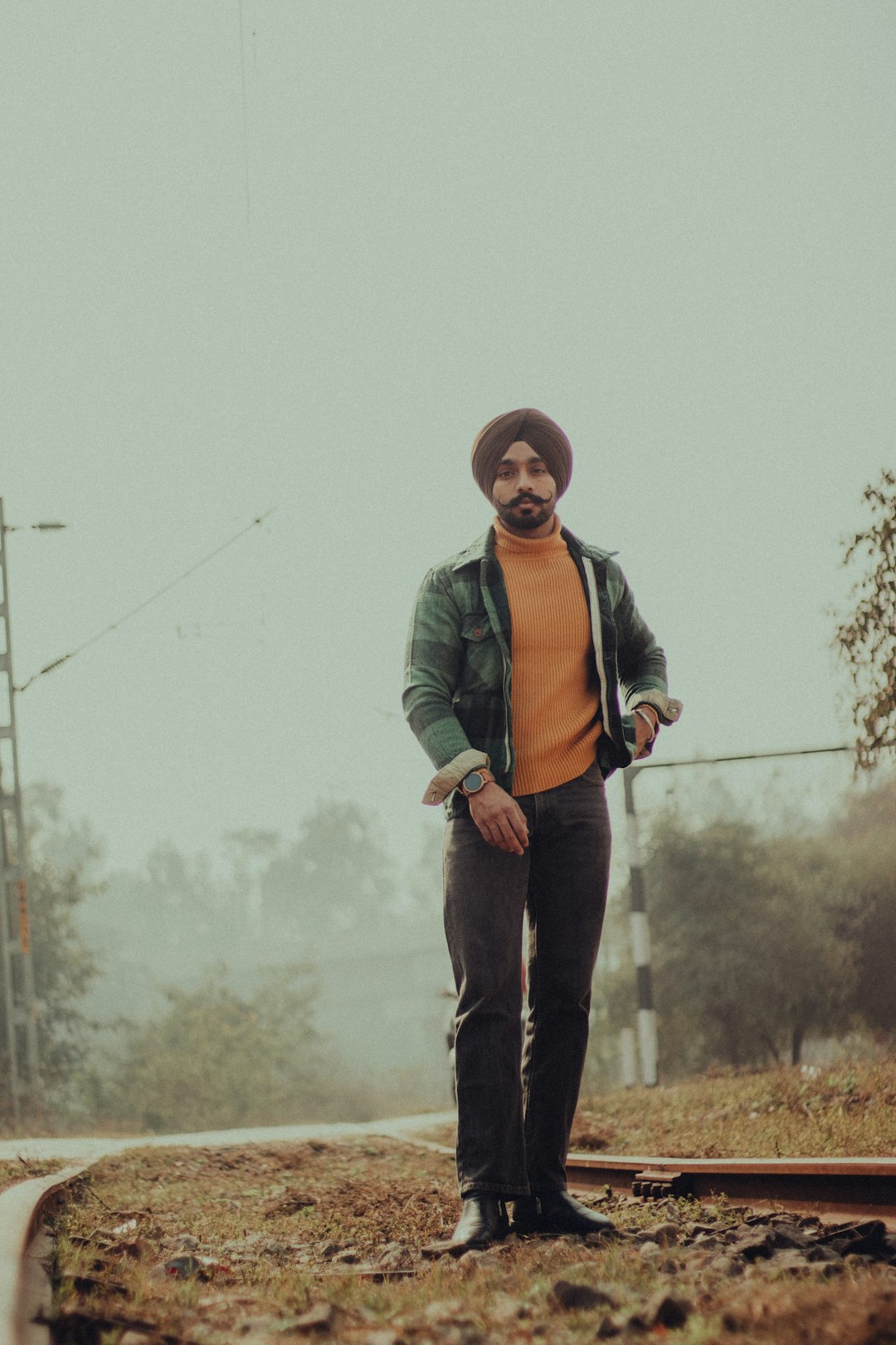 man in green jacket and black pants standing on brown grass field during daytime