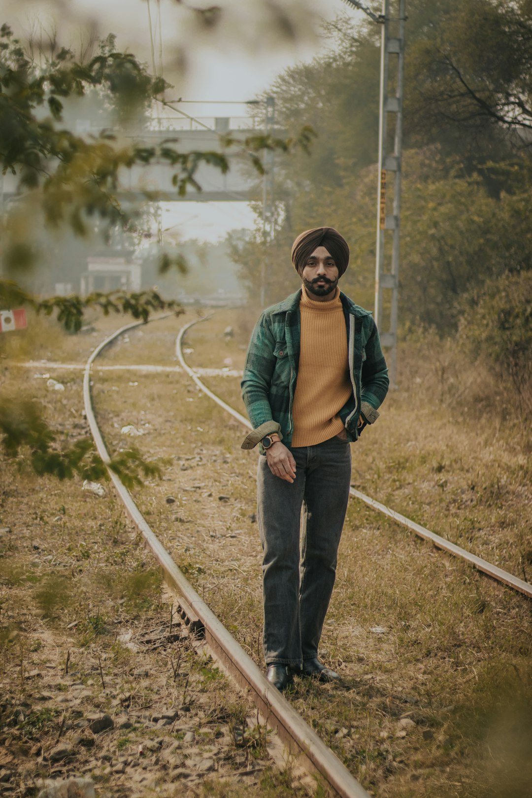 man in green jacket and blue denim jeans standing on brown soil during daytime