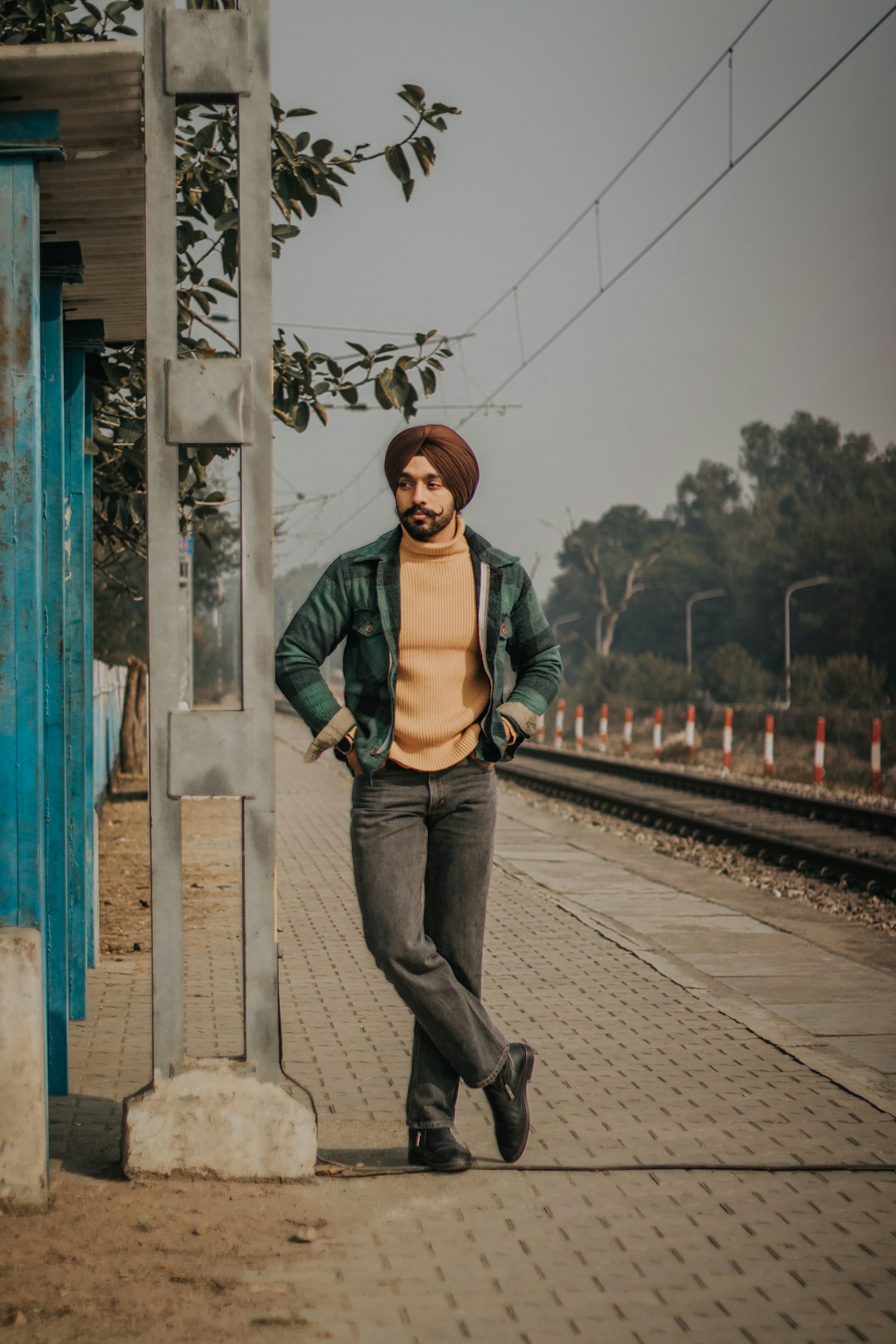 woman in green long sleeve shirt and blue denim jeans standing on bridge during daytime