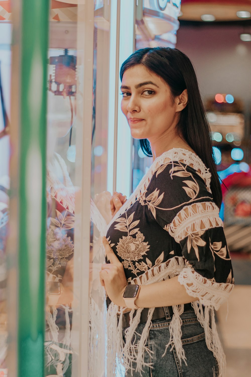 woman in black and white floral dress standing near glass window