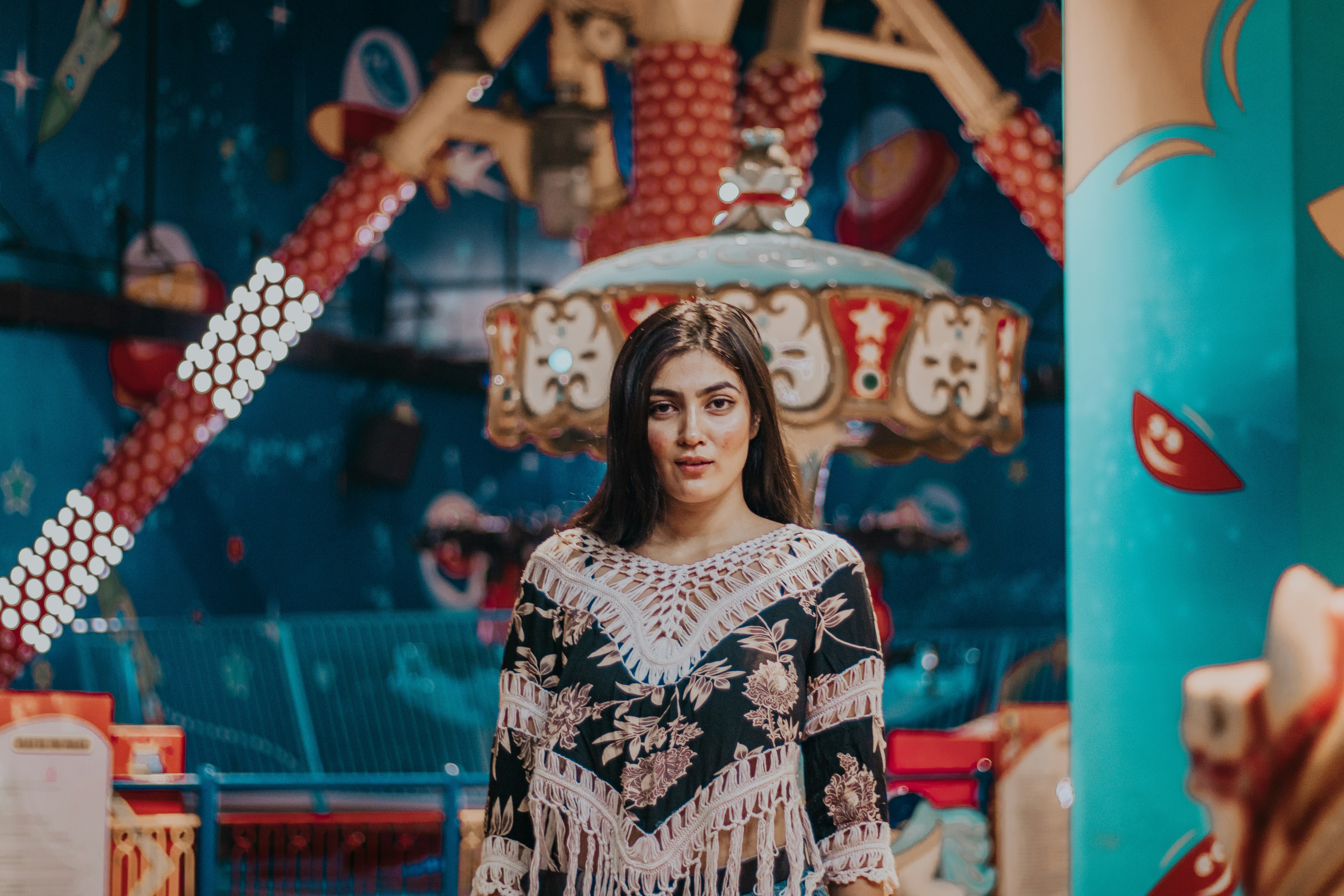 woman in white and black tribal long sleeve shirt standing on red and blue metal frame