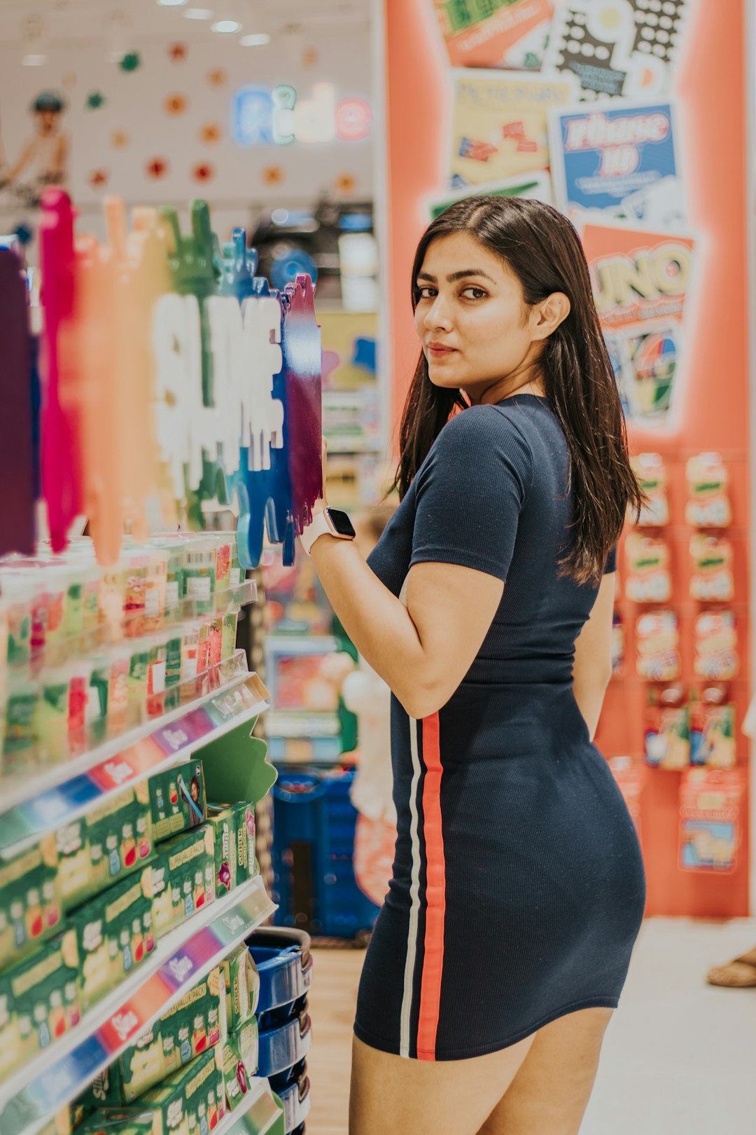 woman in blue shirt and black and red striped pants standing near store