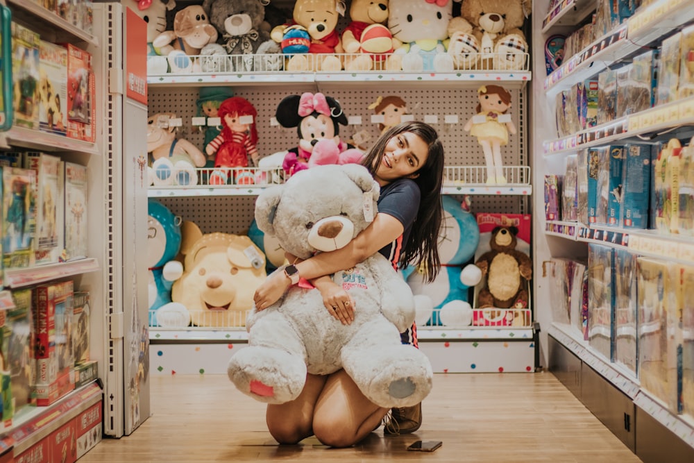 woman in black shirt sitting beside white bear plush toy