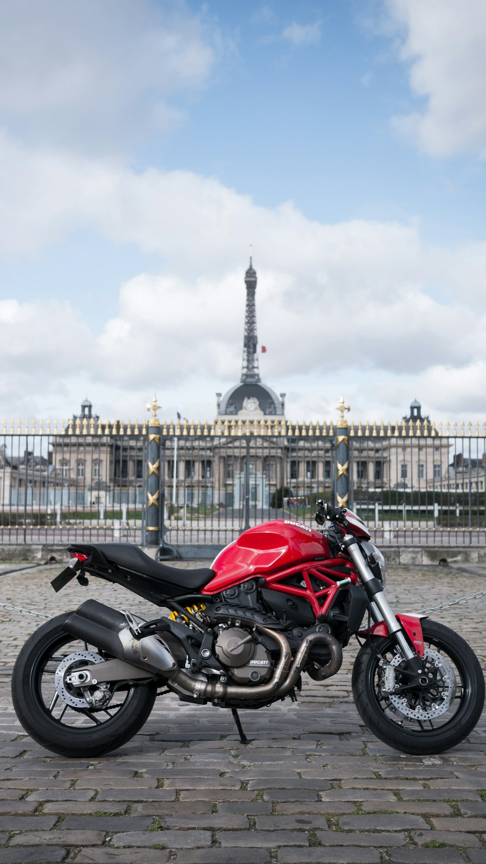 red and black motorcycle parked near white concrete building during daytime