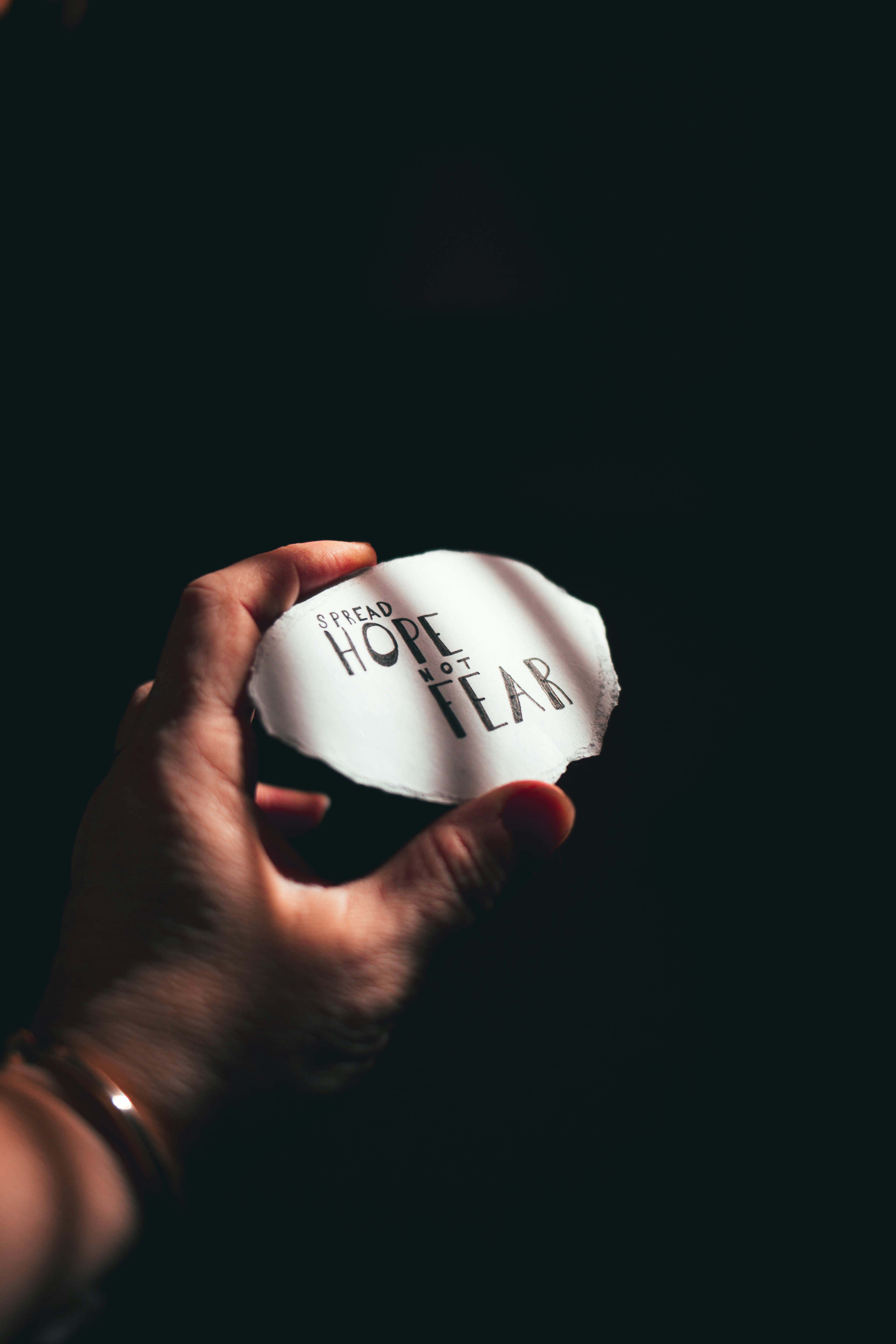 person holding white paper with black text