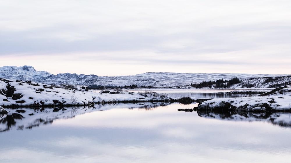 snow covered mountain near body of water during daytime