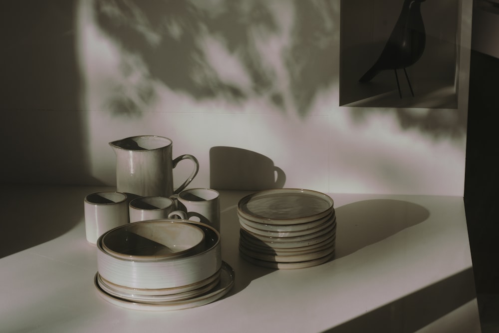 grayscale photo of ceramic mugs on round plates