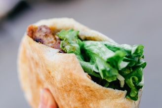 A colorful close-up of a freshly made gyro wrap with juicy meat, fresh vegetables, and sauce wrapped in warm pita bread.