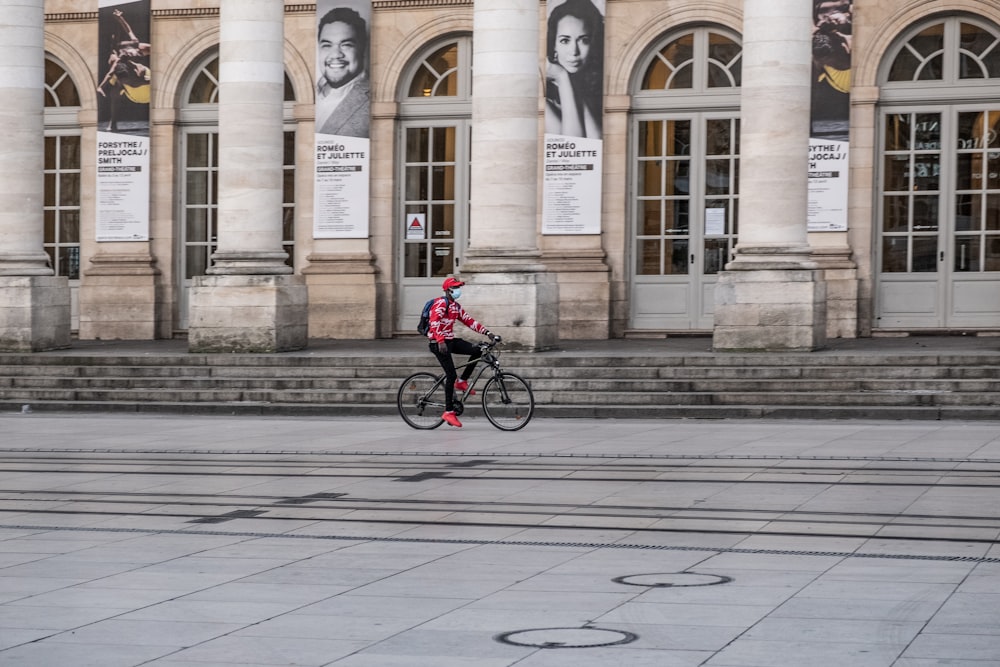 man in red jacket riding bicycle on sidewalk during daytime