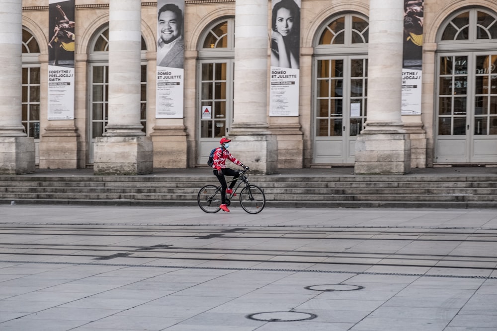 Hombre en chaqueta roja montando en bicicleta en la acera durante el día