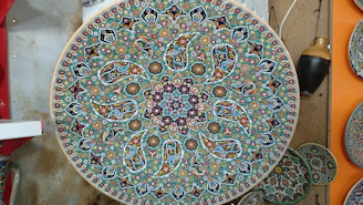 A close-up of a handcrafted brass dinner plate with intricate Indian patterns.