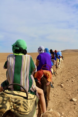people riding horse on brown sand during daytime