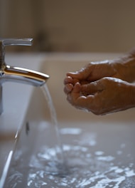 A plumber fixing a sink with tools and water running.