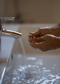 person washing hands on faucet