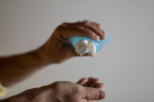 Close-up of a hand holding a small bottle of artificial saliva with a soft blue background