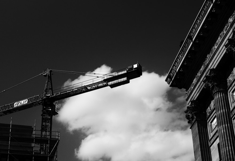 grayscale photo of crane under cloudy sky