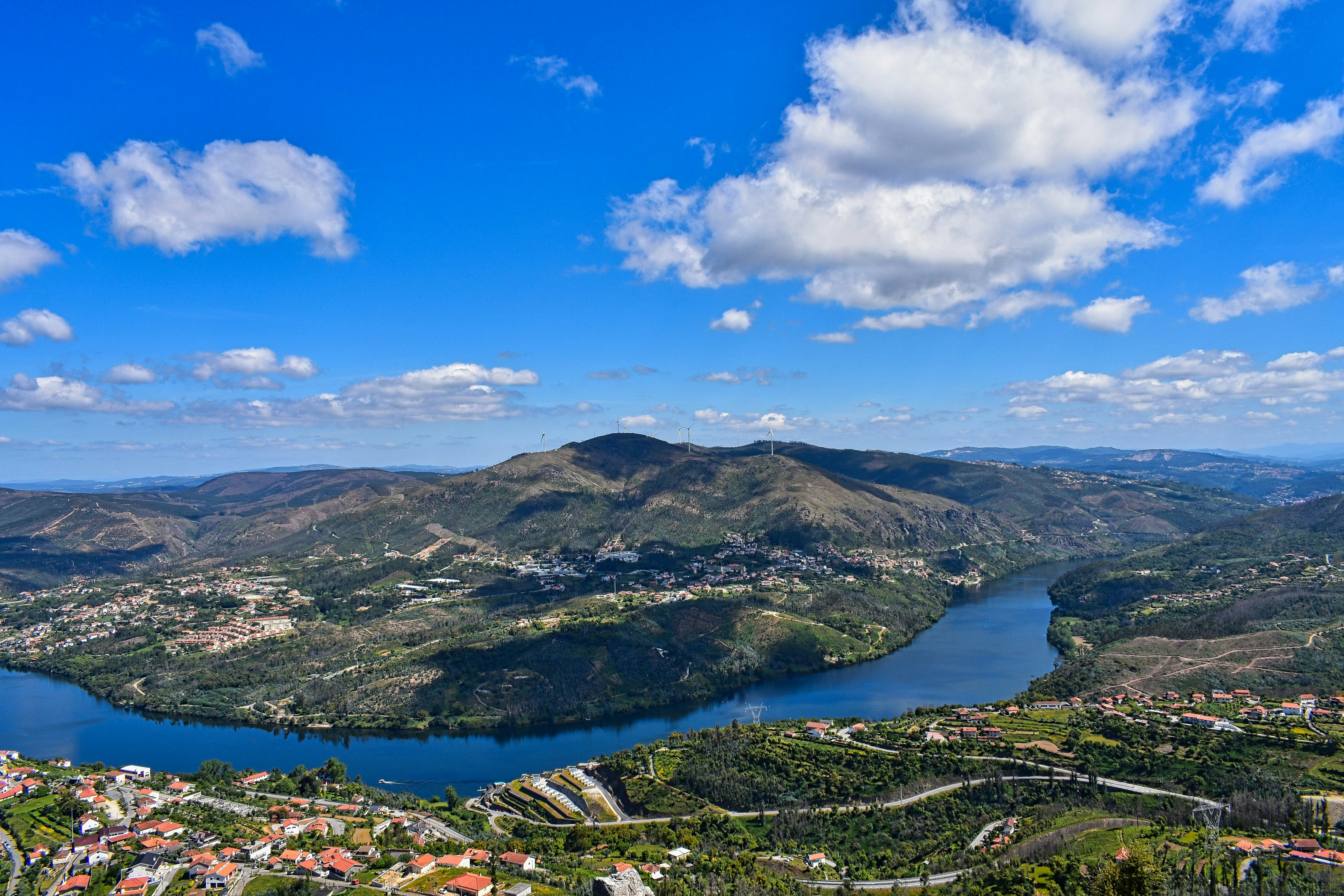 aerial view of green mountains and lake under blue sky during daytime