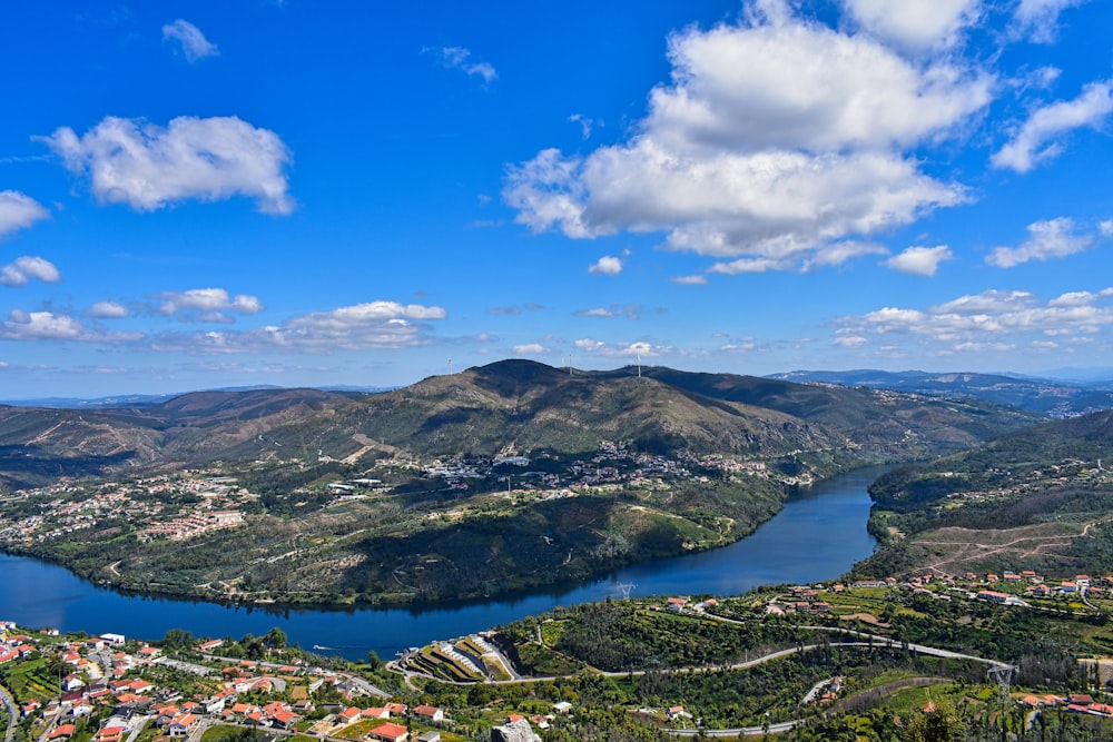 aerial view of green mountains and lake under blue sky during daytime