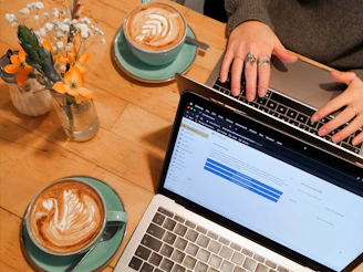person using macbook pro on brown wooden table