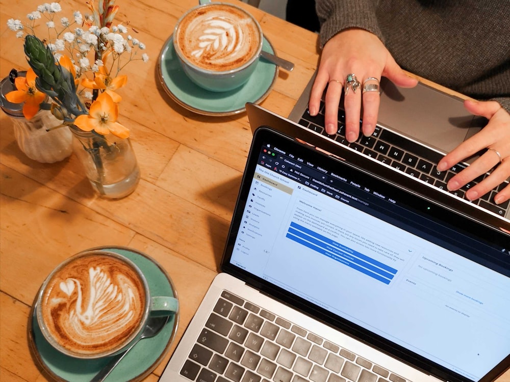 person using macbook pro on brown wooden table