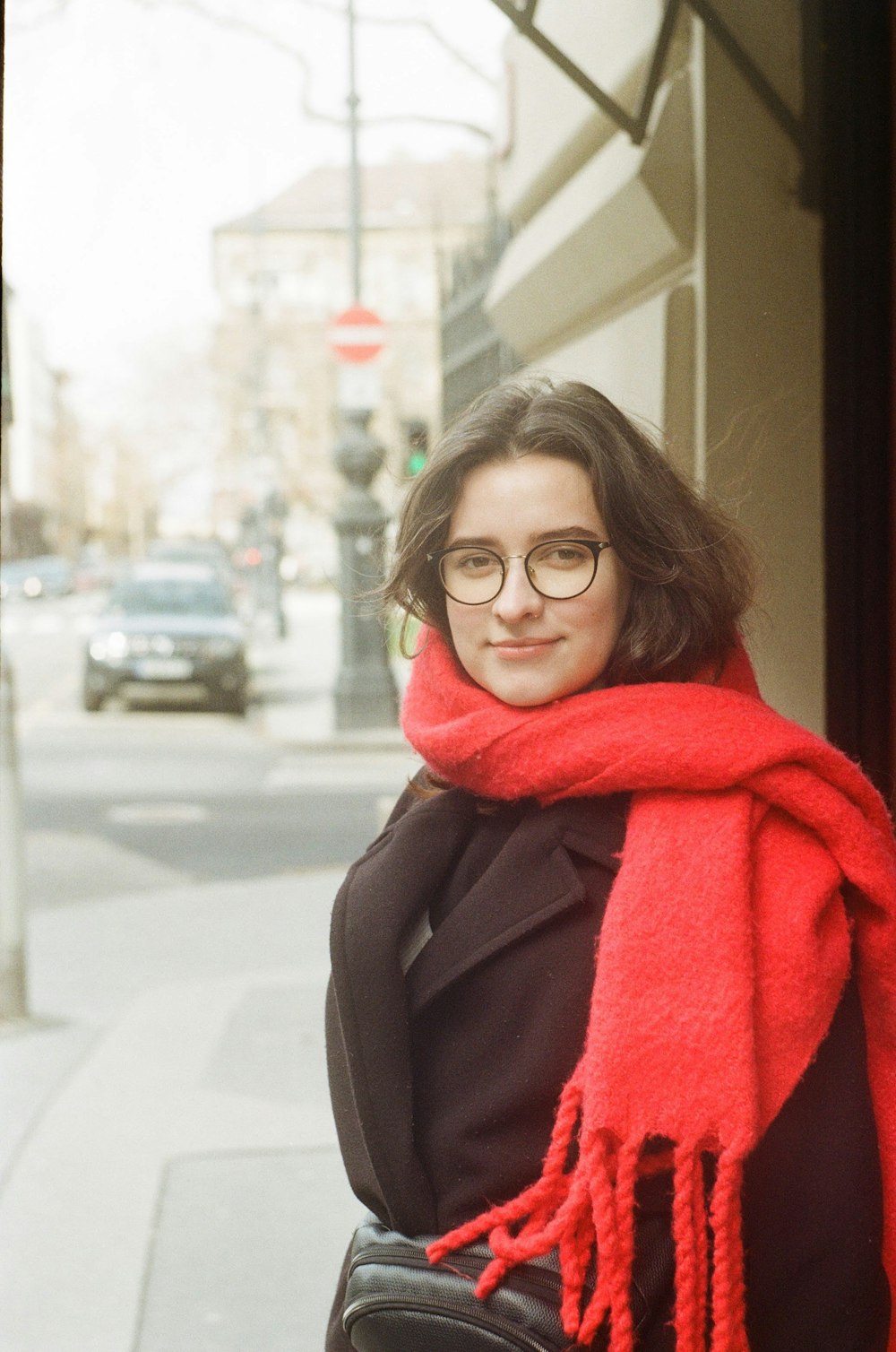 赤いスカーフと黒いコートを着た眼鏡をかけた女性