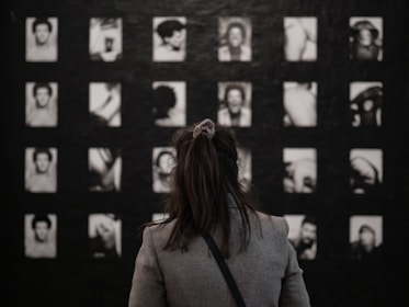 woman in gray coat standing in front of black and white wall