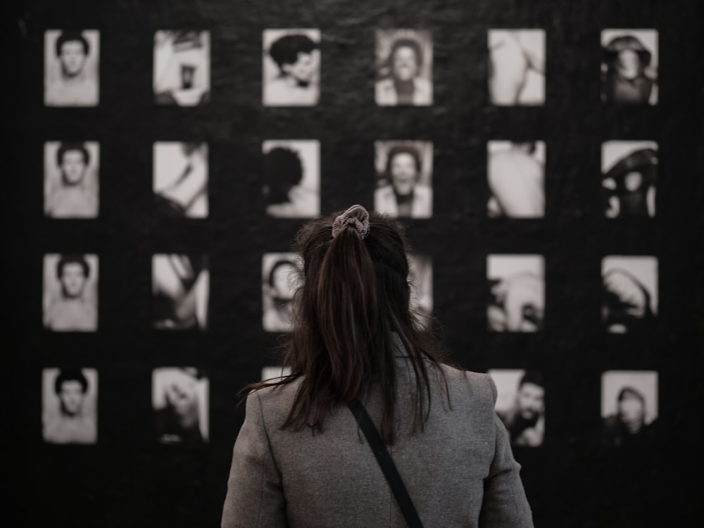 woman in gray coat standing in front of black and white wall