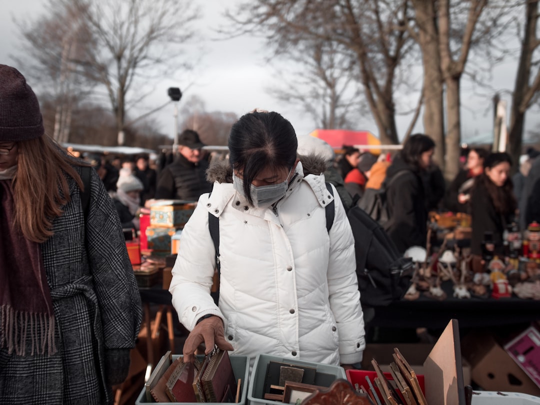 man in white jacket standing near brown wooden table, Girl with mask