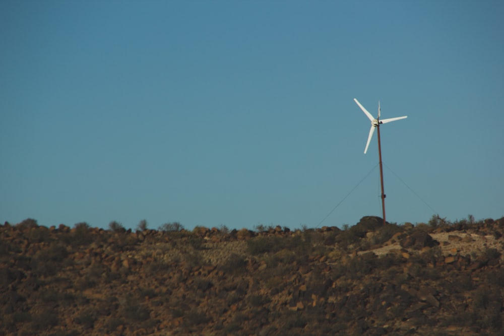 white wind turbine on brown field under blue sky during daytime