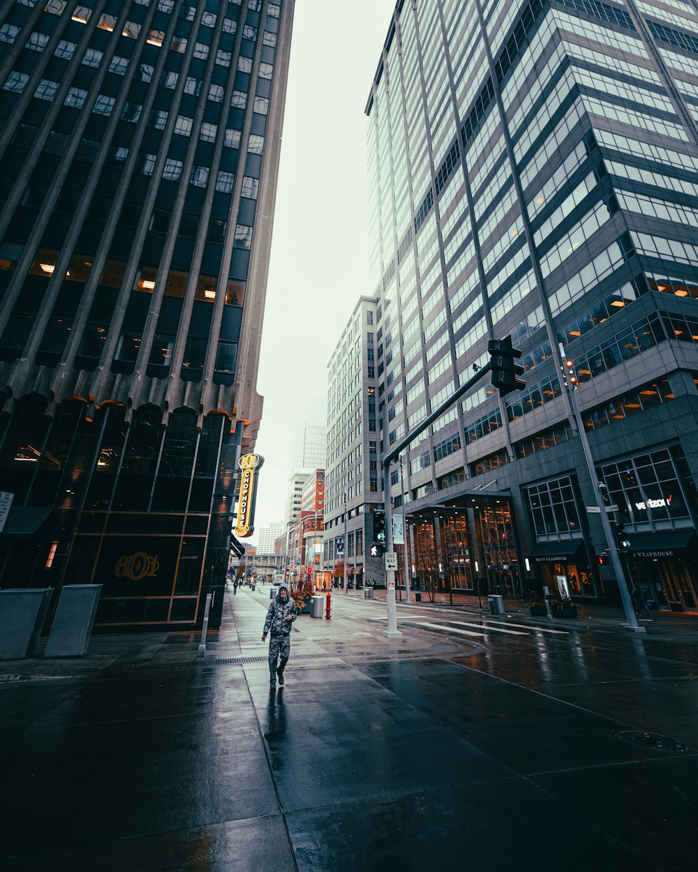 man in black jacket and pants walking on sidewalk during daytime