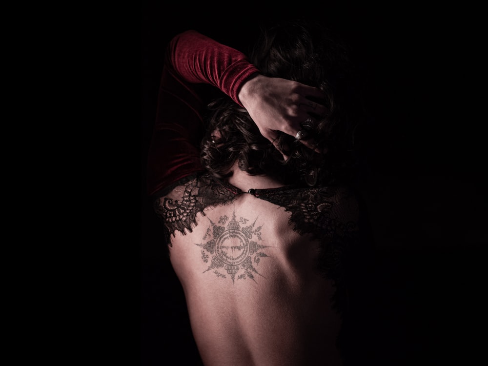 Mujer con camisa roja de manga larga con tatuaje floral negro en la espalda