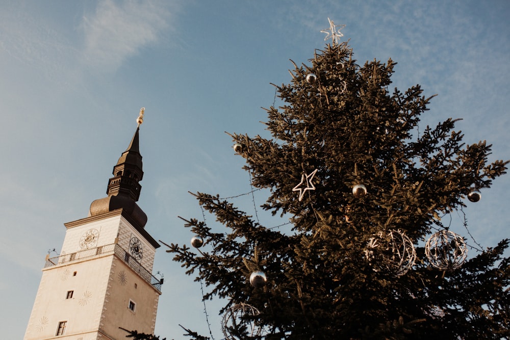 a tall clock tower next to a christmas tree