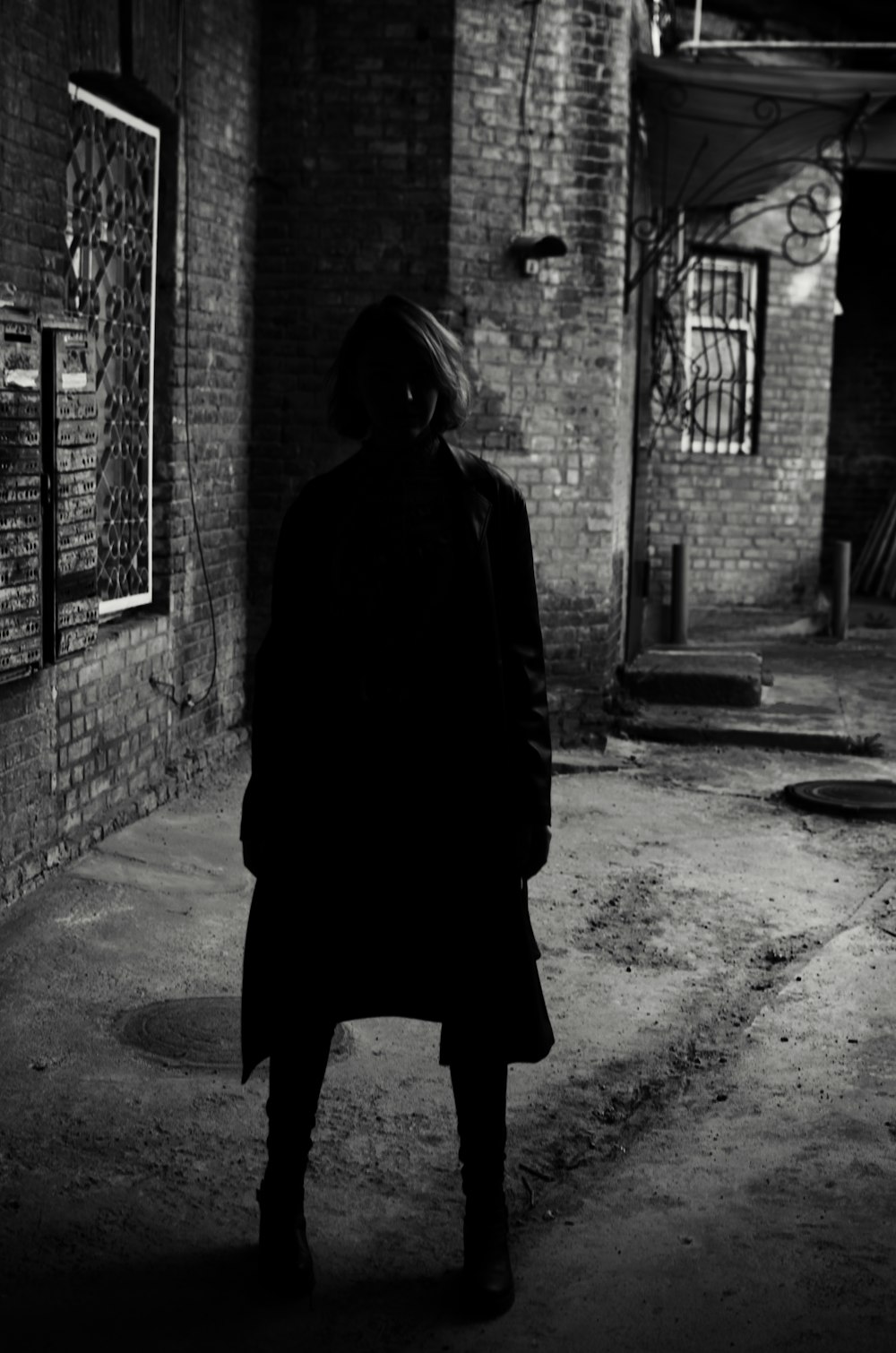 person in black hoodie standing on sidewalk during daytime