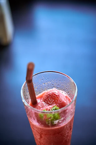 Close-up of a signature slush drink with vibrant colors served in a stylish glass on a dark wooden table.