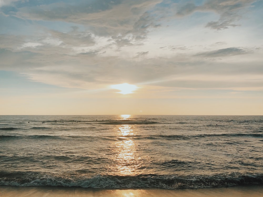 body of water under cloudy sky during sunset