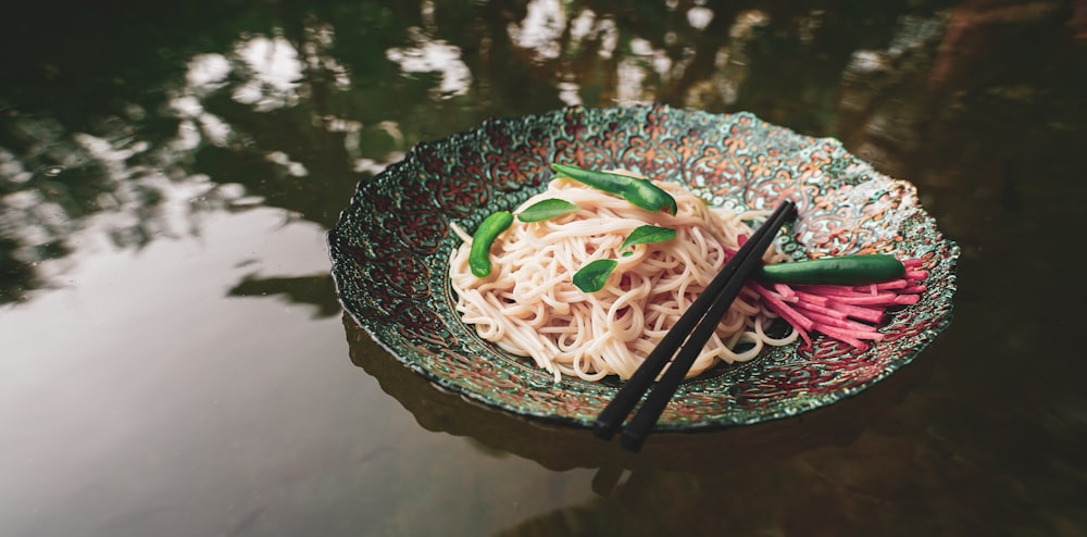 white and green noodles on black round plate