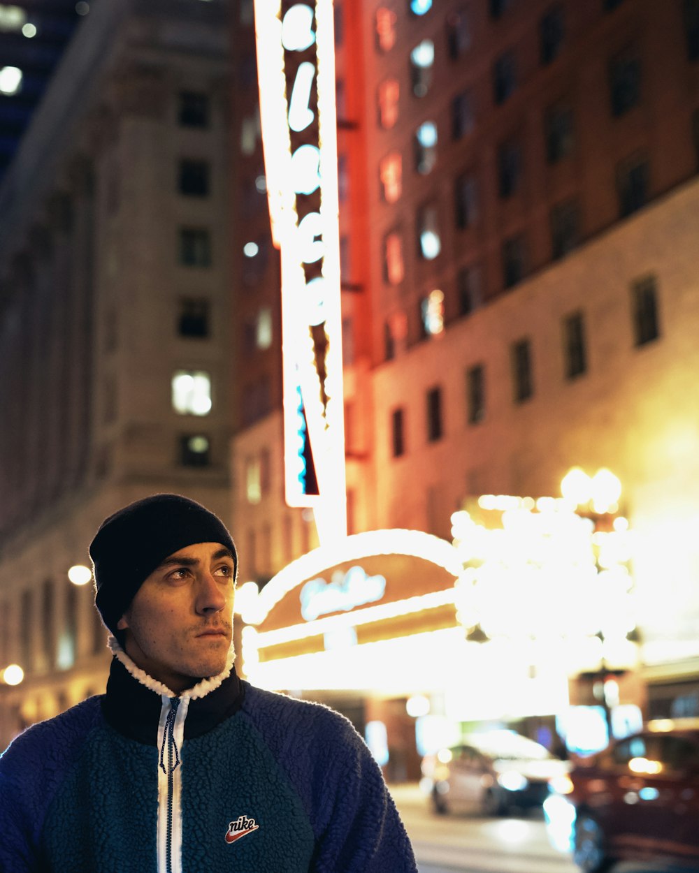 man in blue knit sweater and white knit cap standing near brown concrete building during daytime