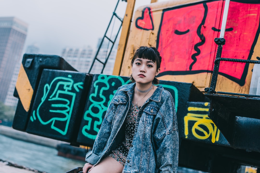 woman in blue denim jacket standing near graffiti wall during daytime
