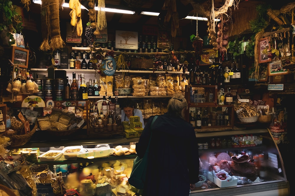 man in black jacket standing in front of food display