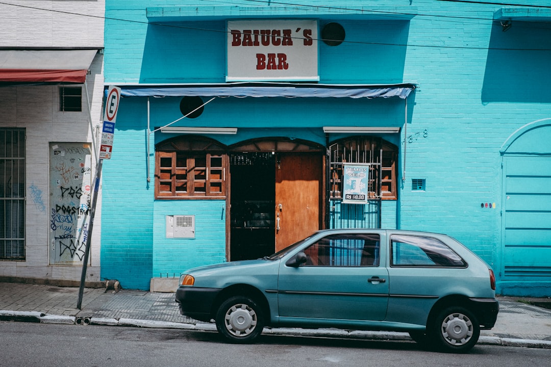 blue sedan parked beside blue and white building during daytime