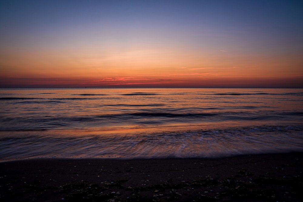 ocean waves crashing on shore during sunset