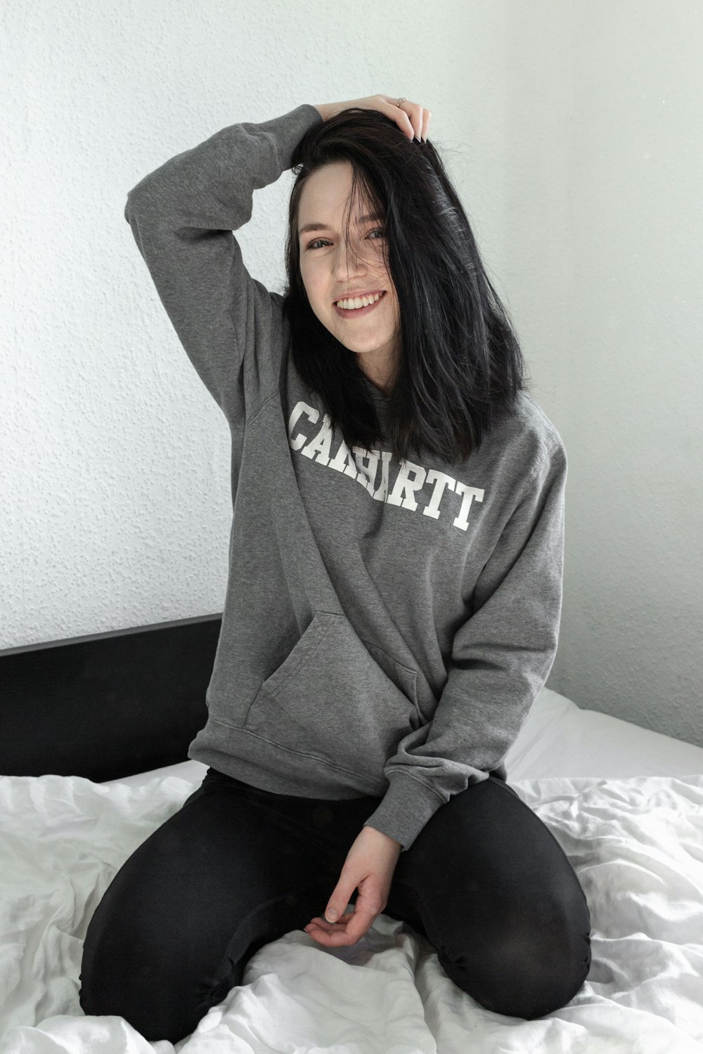 woman in gray hoodie sitting on bed