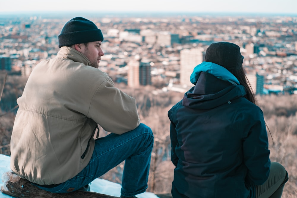 man and woman standing on top of building looking at city during daytime