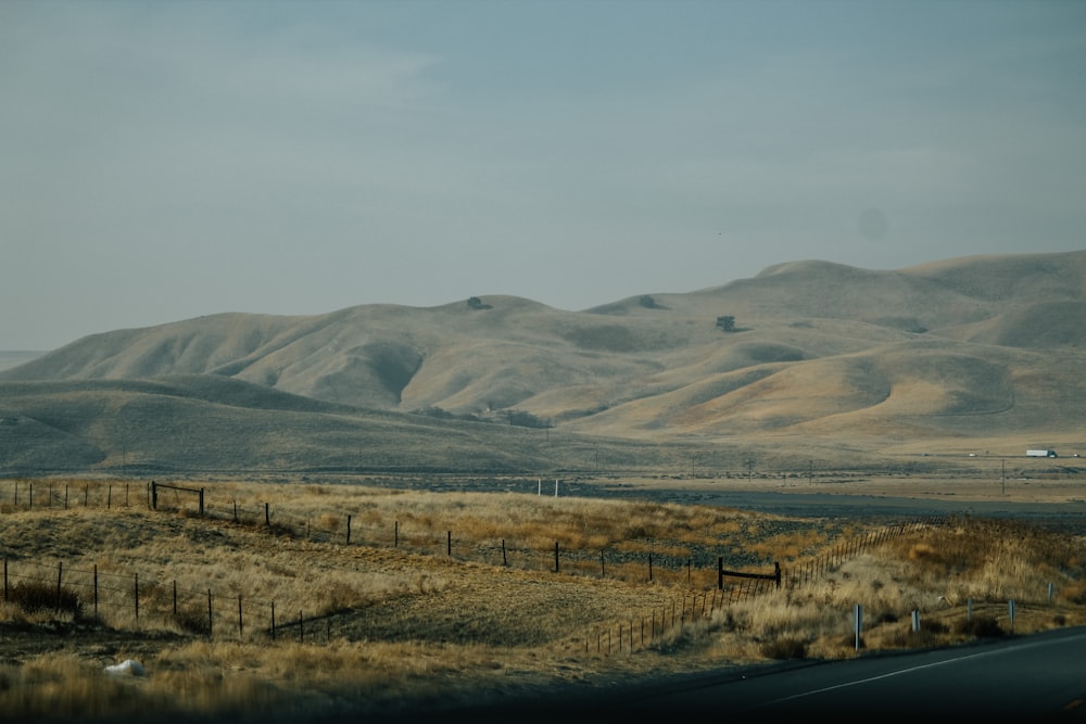 gray asphalt road in between brown grass field during daytime