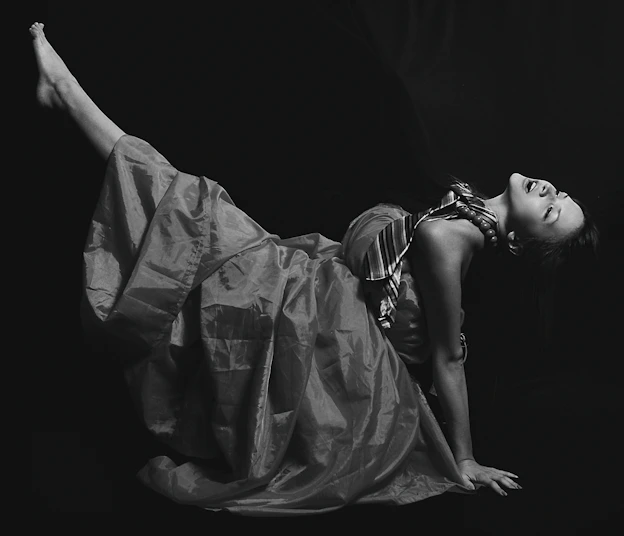 A striking black-and-white photograph of a model wearing a sculptural garment, framed against a modern Chicago architectural backdrop.